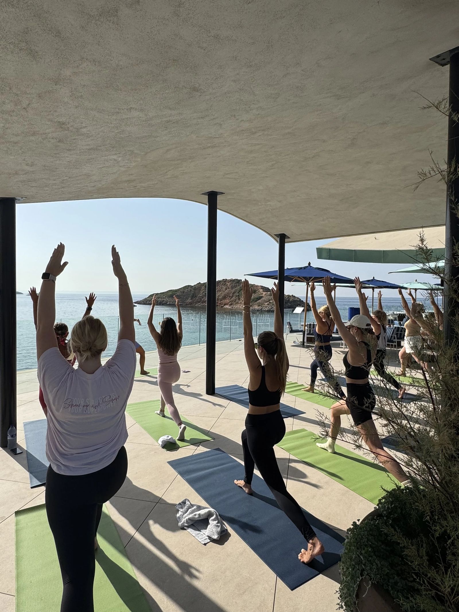 Participants estirant-se sota la pèrgola en una sessió de benestar en un beach club de Mallorca